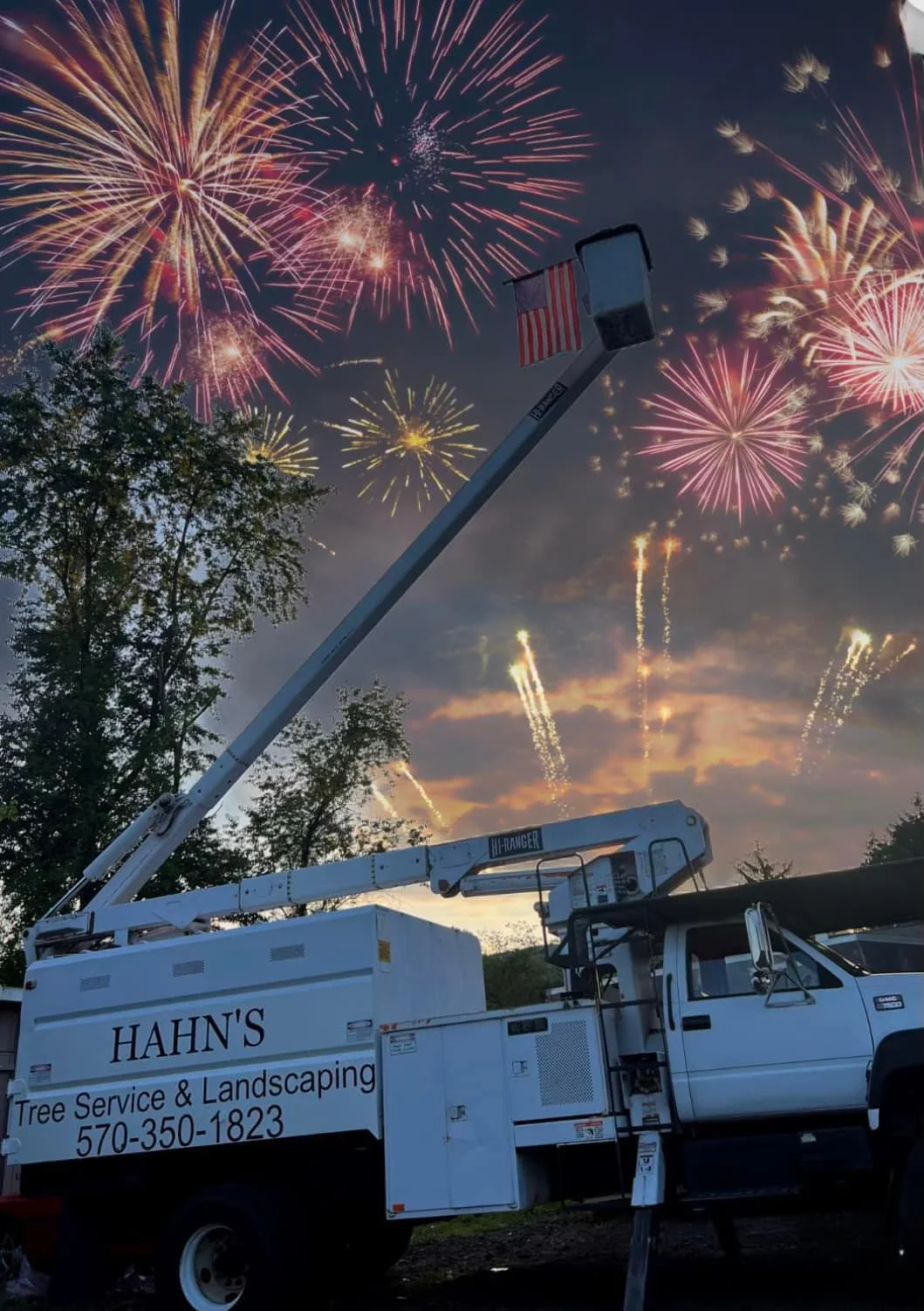Bucket truck flying a large American flag beneath fireworks at night