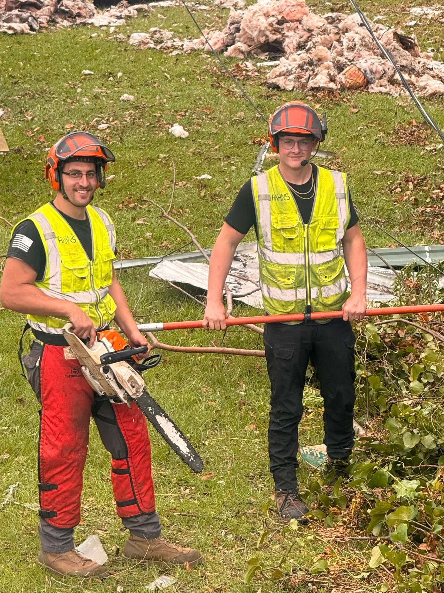 Two crew members cutting up storm debris with chainsaws